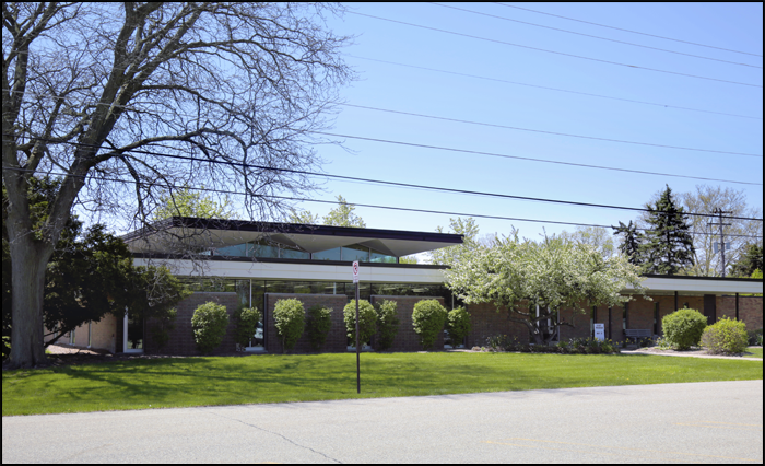 exterior view of library building with modern roof design trees and landscaped lawn in front